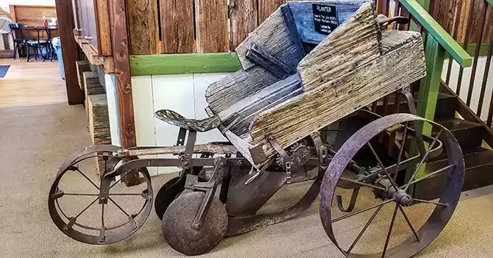 A pototo digging machine consisting of a front wheel, two back wheels, discs to turn over the soil, and a box on top. 