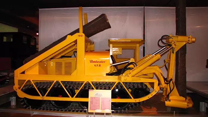 Yellow tracked machine with hydraulics on one end. 