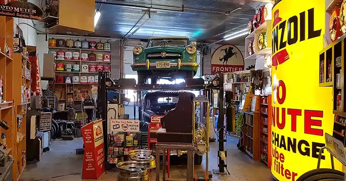 Hoist with one car on top and one below, along with all of the stock you'd expect to see in a 1950s garage.