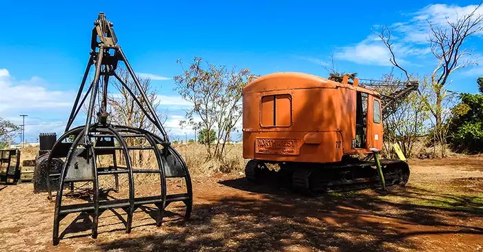 Large black device used to grab the sugar cane and an orange machine. 
