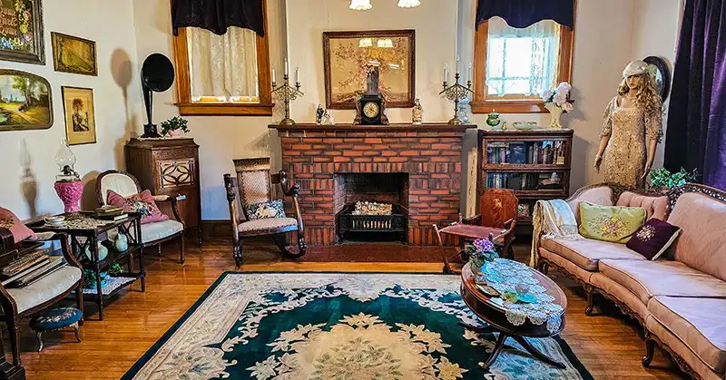 Fireplace in the center of the room with chairs and sofas to the sides. 