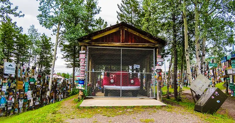 A red vintage truck from the 1940s in an enclosure with signs all around it. 