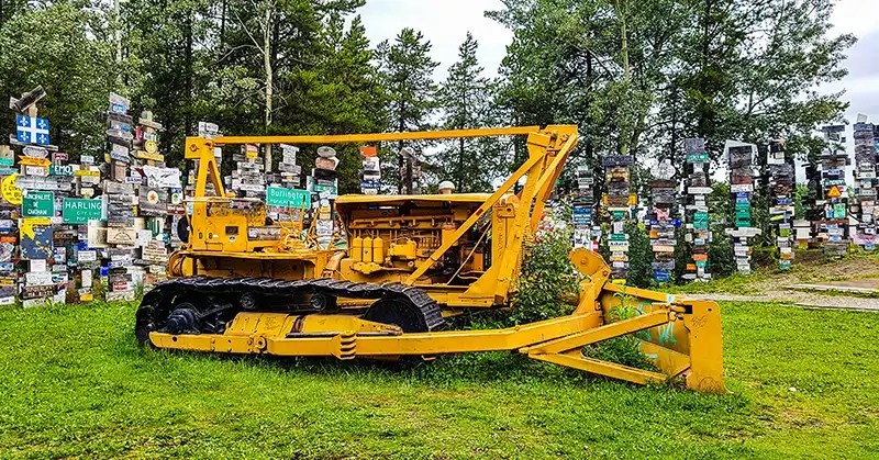 Caterpillar with thousands of signposts behind it. 