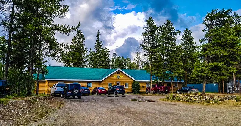 Log building with spruce trees around it