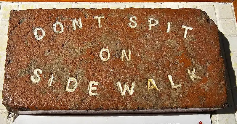 Brick stamped with "Don't Spit on the Sidewalk."