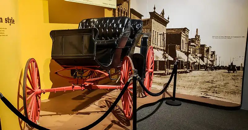 Carriage in front of wall-size photo of Main Street, 1910, in Tower, Minnesota.