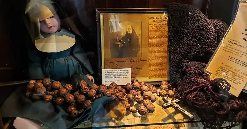Display of doll dressed as a nun and photograph with clippings about Mother Mary Clare (1875 - 1935).