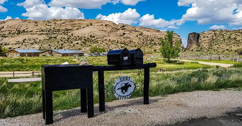 Devil's Gate - the V cut into the granite in the distance, along with a Pony Express marker and historic Sun Ranch buildings.