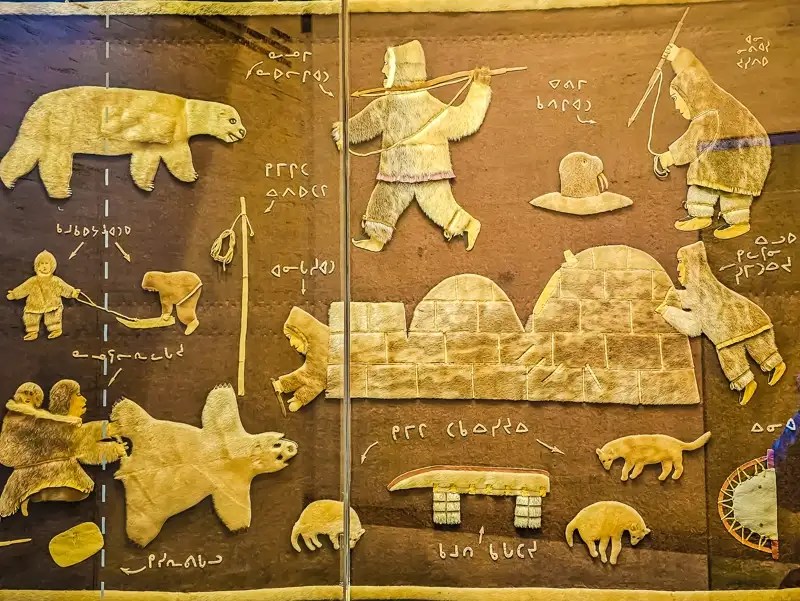 Textile wall hanging showing traditional Inuit life. 