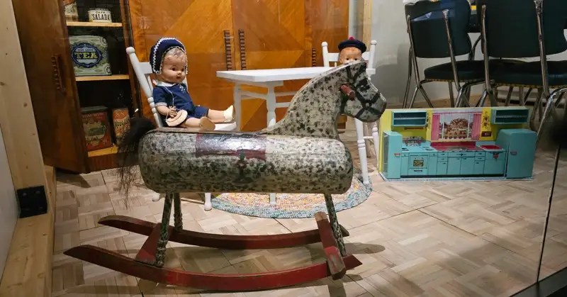 Children's rocking horse, doll, and kitchen set next to family kitchen table and chairs.