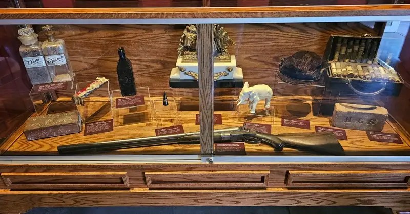 Assorted artifacts in a glass case including an 1876 Double-barreled shotgun. 