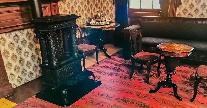Sofa, chairs around gaming table, and a fireplace in Mackenzie House in Toronto.