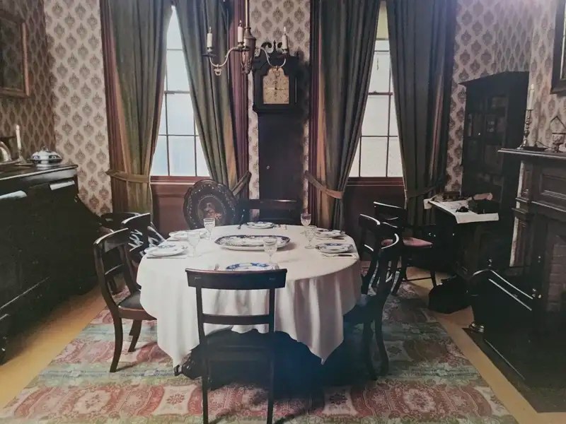 Dining table and chairs with China on a linen tablecloth in Mackenzie House.