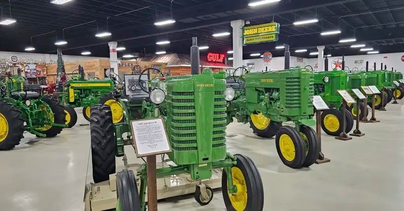 Rows of green John Deere tractors with information signs in front of each one. 