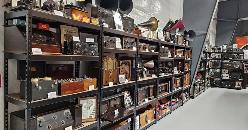 Five rows of vintage radios on shelving units. 